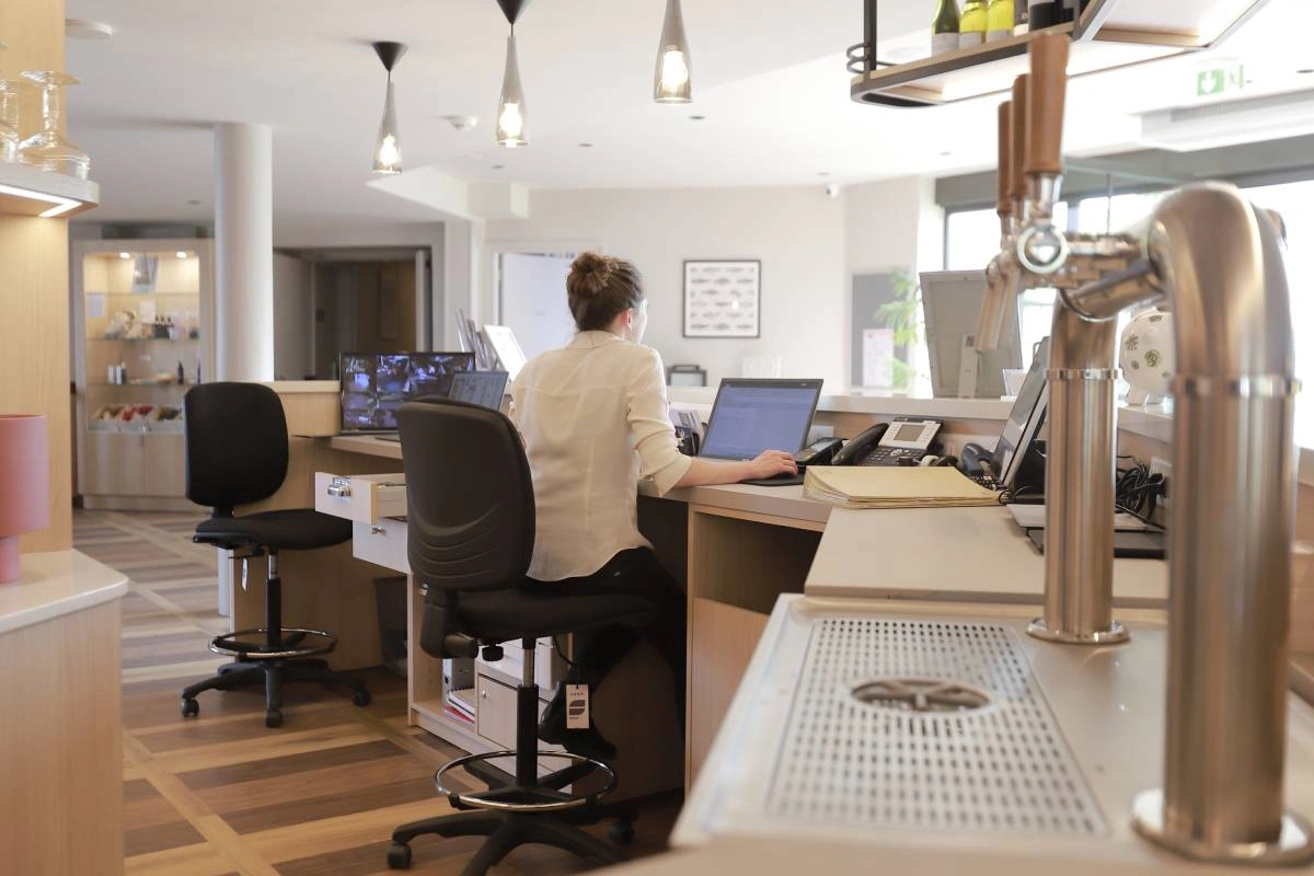 Receptieruimte van Hôtel Antares & Spa Honfleur met personeel dat gasten verwelkomt en nuttige informatie verstrekt.