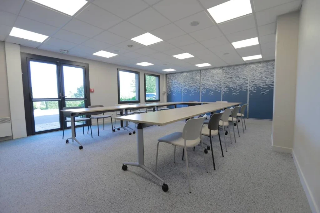 Salle de séminaire lumineuse de l’Hôtel Antares & Spa Honfleur, équipée de tables modulables et de chaises pour réunions et événements professionnels.